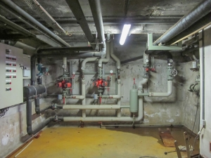 Local technique – Expertise en Installation et Entretien Vue intérieure d’un local technique équipé de tuyauteries et de systèmes de circulation hydraulique, illustrant le savoir-faire d’Agir dans l’entretien et l’installation d’équipements de chauffage et de climatisation.